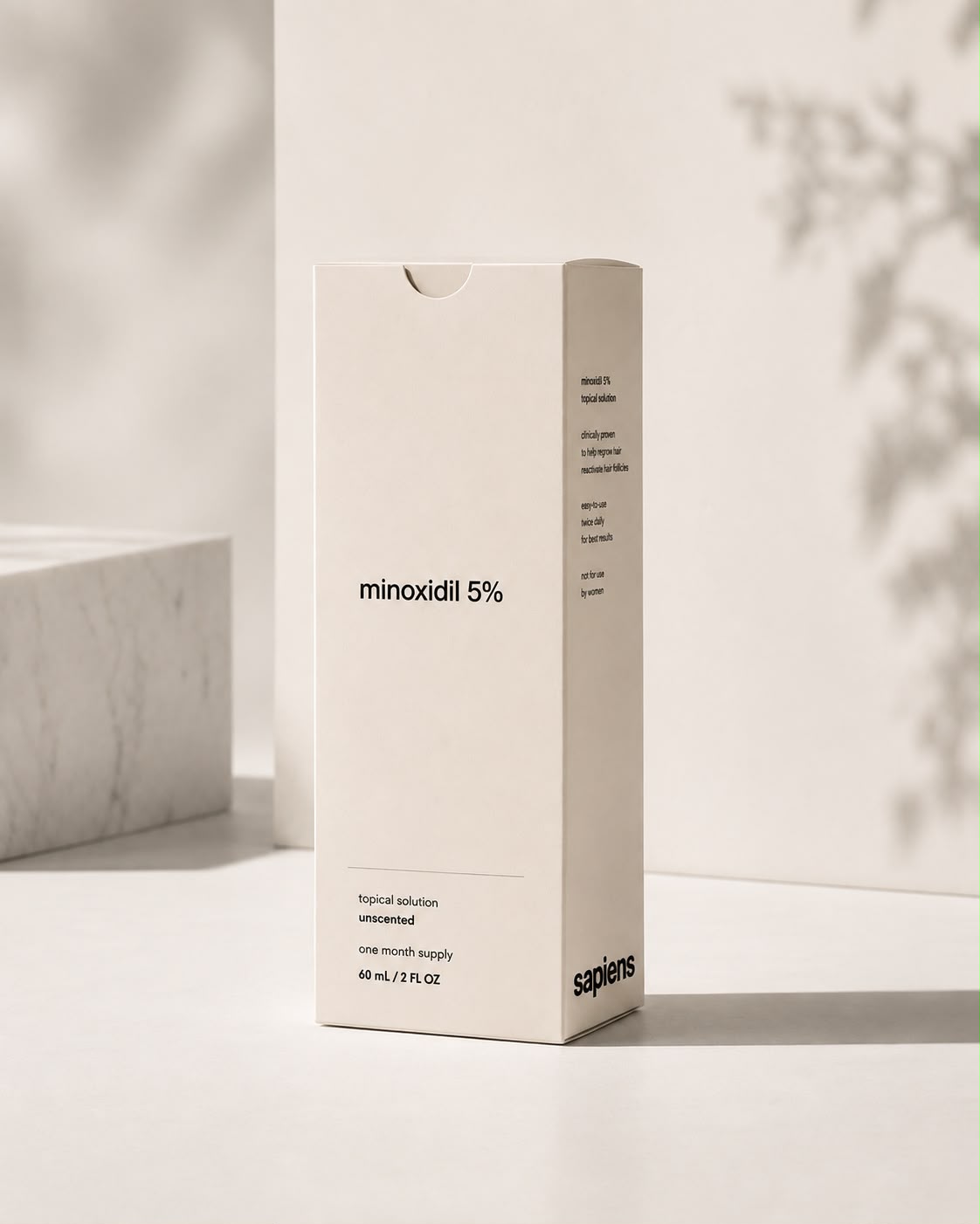 A Sapiens-branded carton of minoxidil 5% topical solution, 60 mL, standing on a pale surface in soft daylight